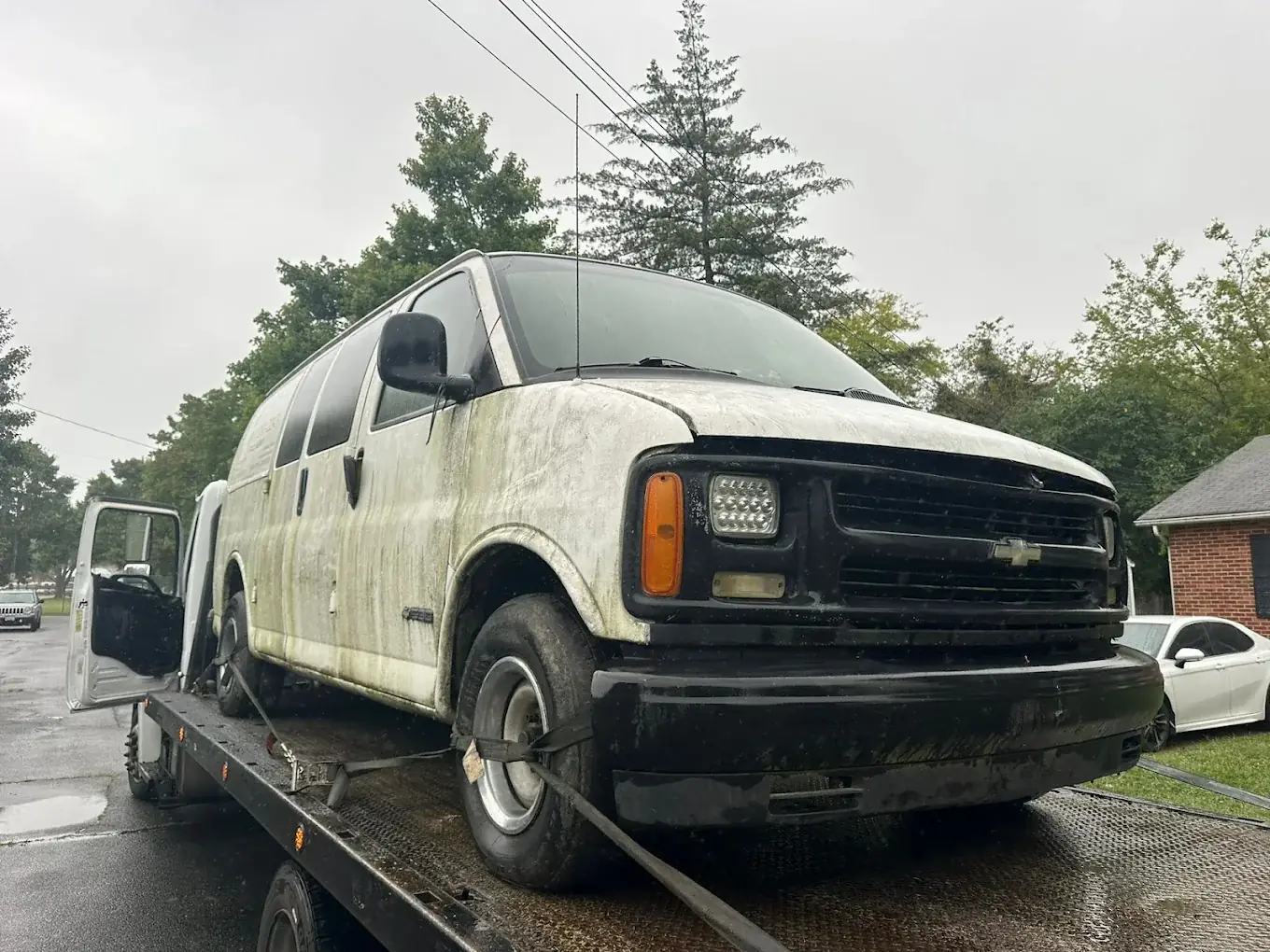 Weathered Chevrolet Express cargo van on a flatbed for junk van removal in Springfield, VA