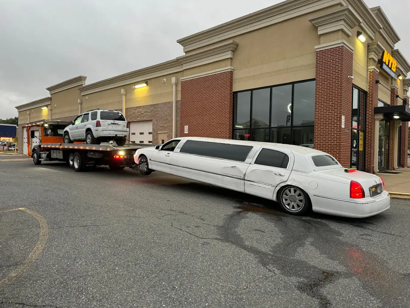 Fairfax Junk Cars Removal towing a white stretch limousine and an SUV in Northern Virginia